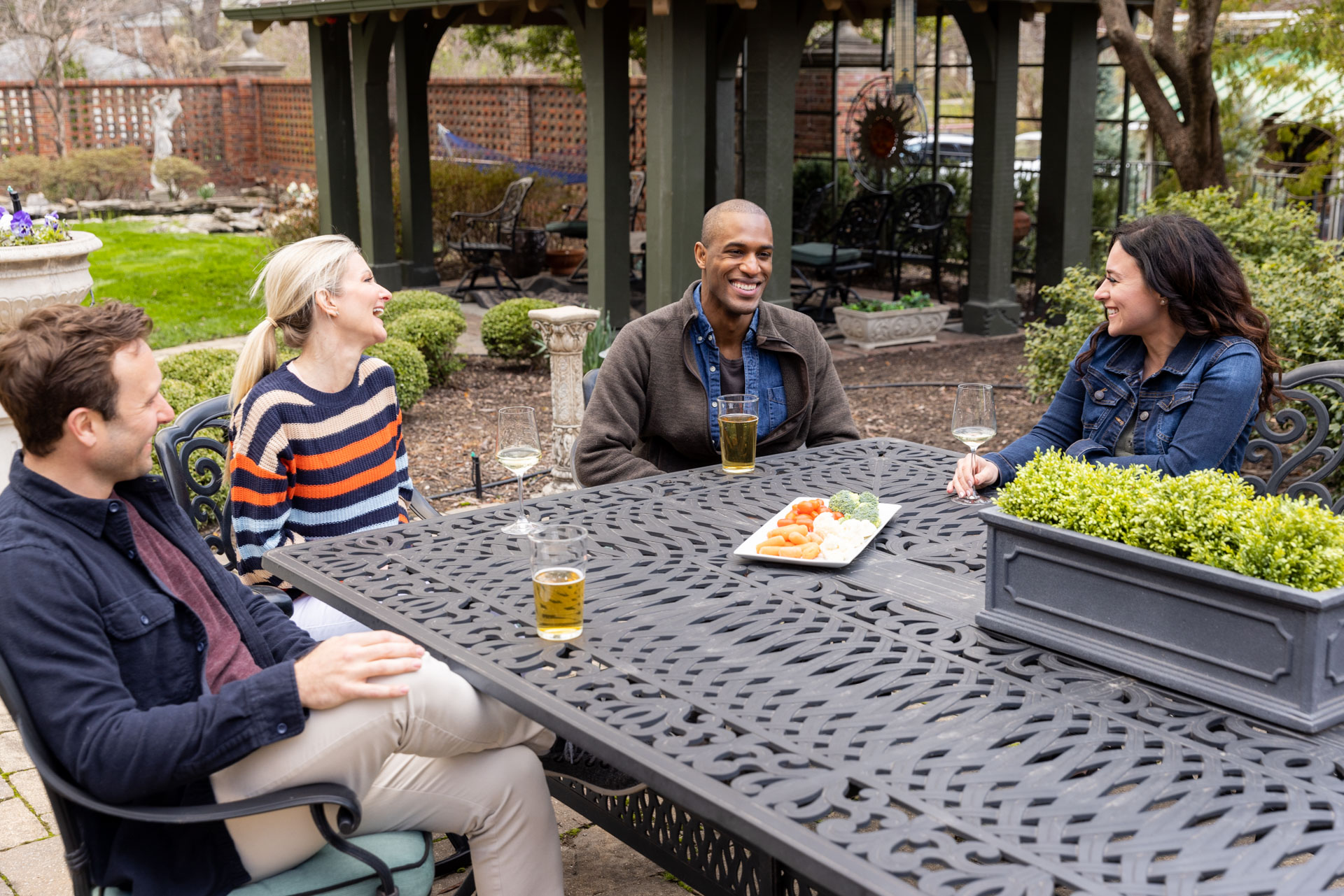 Two men and two women sit outside, talking and laughing.