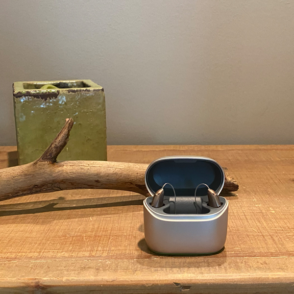 Two Injoy Choice hearing aids in the charger on a table