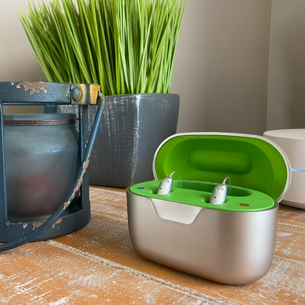 Two Injoy Security hearing aids in charging case on a table