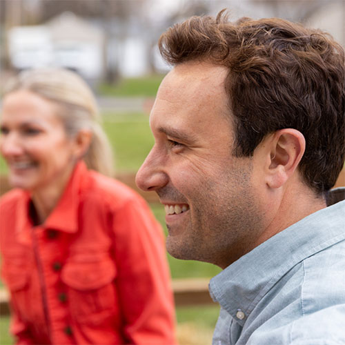 A man in his 40s happy to be wearing Injoy hearing aids in a fun, social environment.