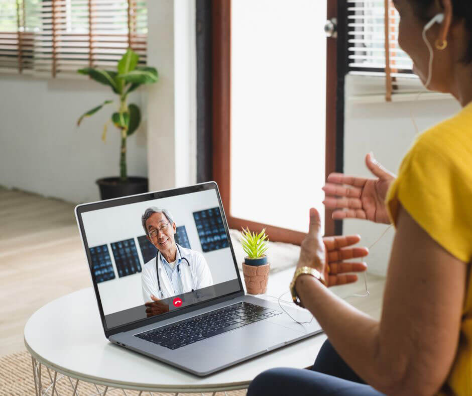 woman sits and has a telehearing appointment on her laptop.