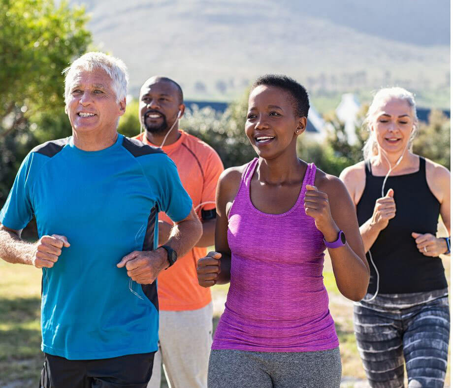 Four older adults jog and talk together on a desert trail. 