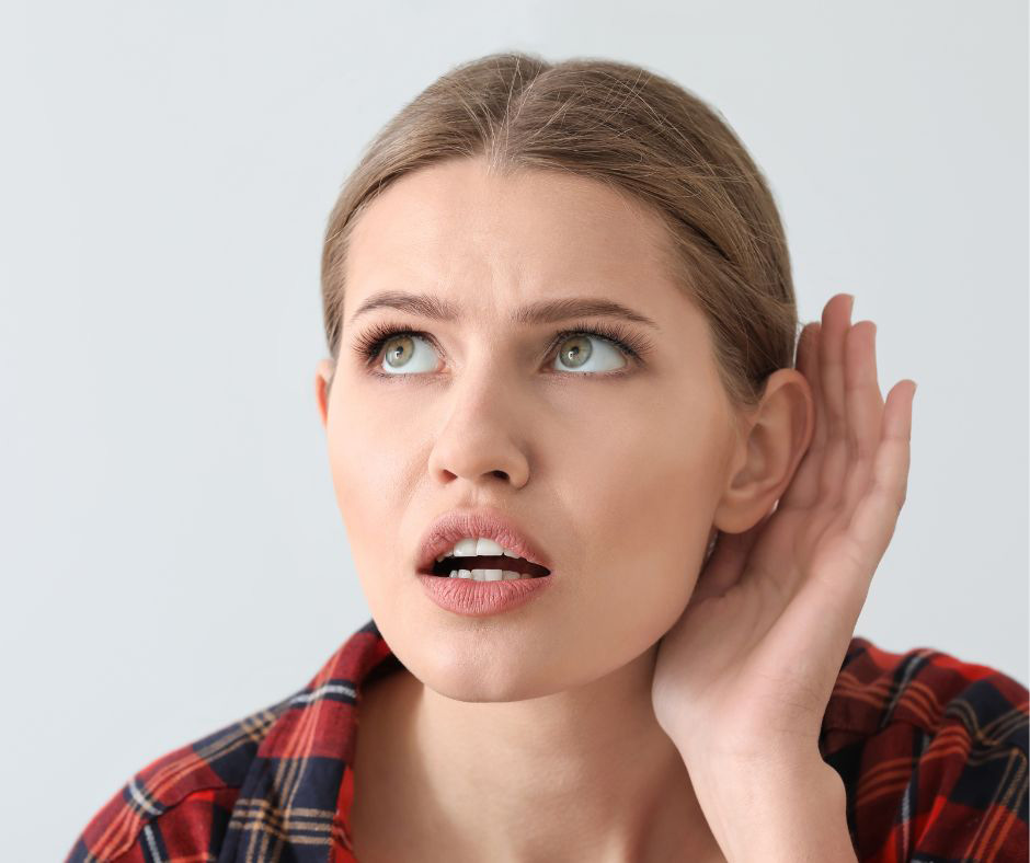 A woman cups her hand around her ear to hear better. 