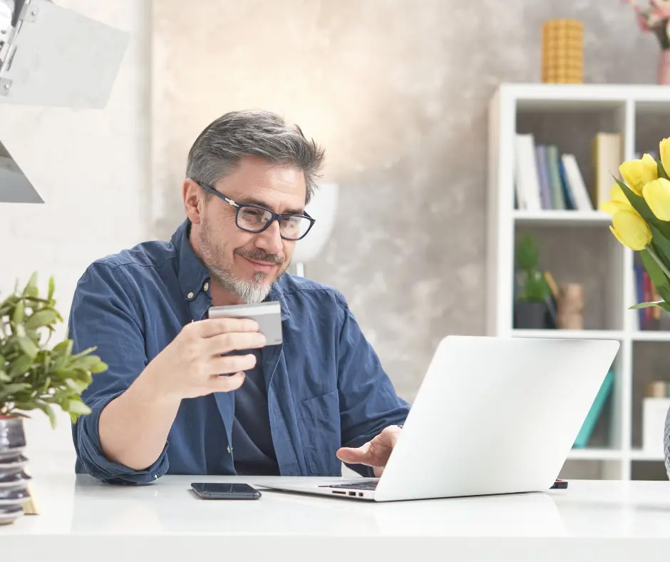 A man holds his credit card while shopping online.