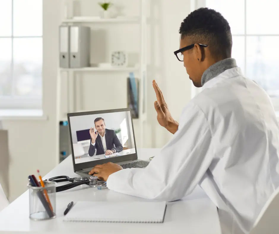 An audiologist starts a telehearing appointment with a wave. 