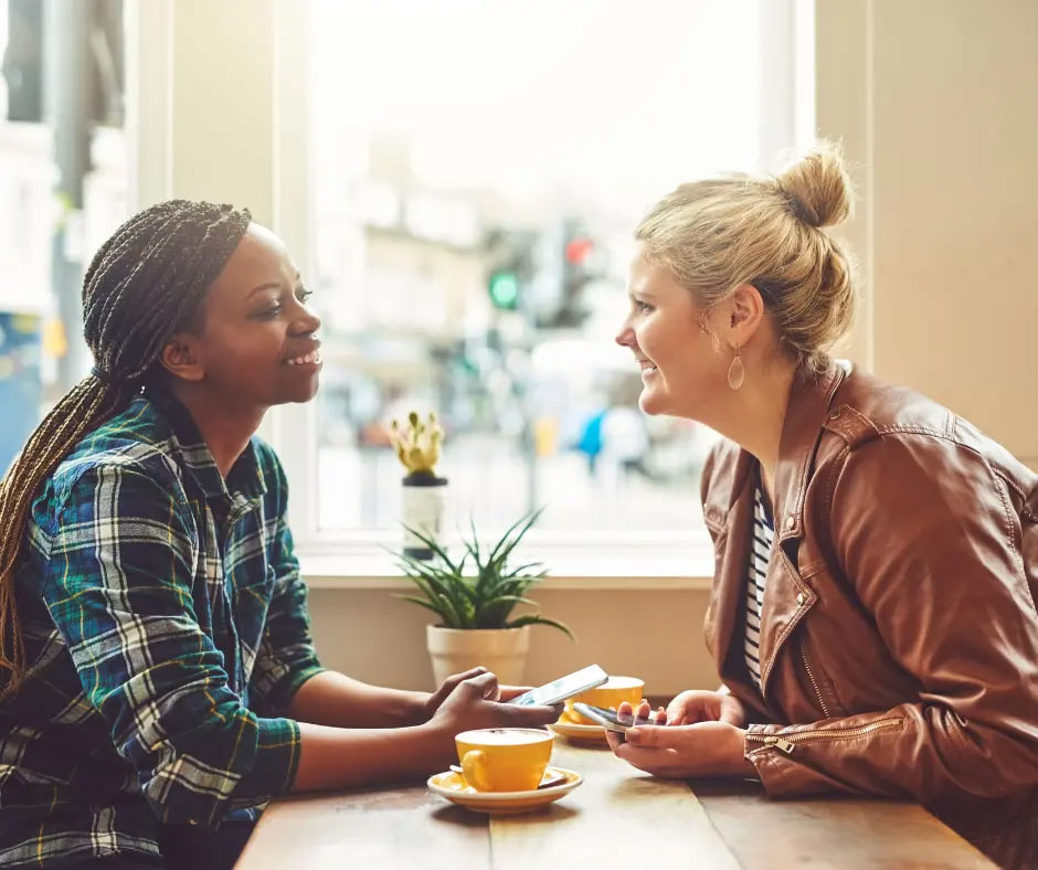 Two friends talk at a coffee shop.