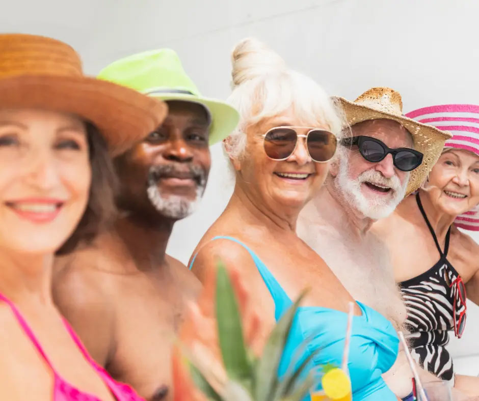 Cheerful older people sit at the edge of a pool. 