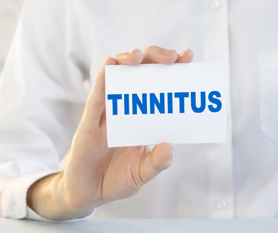 A white-coated person holds a card that says, “Tinnitus.”